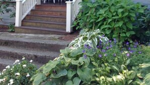 Una casa a due piani con un portico, una bandiera e dei gradini che portano all'ingresso.