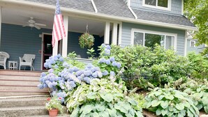 Una casa con portico, bandiera americana e diverse piante.