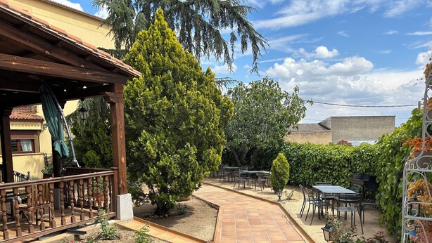 Un espace patio aménagé avec des sièges d’extérieur, une pergola et une variété de plantes.