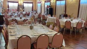 Une grande salle à manger avec de nombreuses tables rondes dressées pour un repas, chacune étant agrémentée de chaises et de couverts.