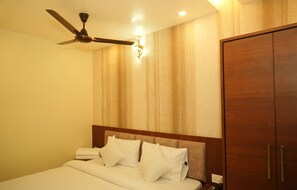 Une chambre d’hôtel équipée d’un lit, d’un ventilateur de plafond, d’une armoire et d’un luminaire fixé au mur.