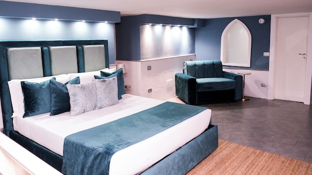 A modern bedroom with a large bed, a chair, a vanity, and a mirror. - A un passo dal Castello Maschio Angioino (Naples)