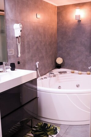 Une salle de bain moderne avec une baignoire blanche, un meuble-lavabo avec un miroir et un sèche-cheveux fixé au mur.