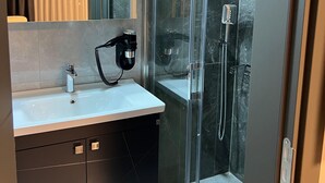 A modern bathroom with a glass-enclosed shower, a white sink, and a mirror above the vanity. - ZULU SUITES (Istanbul)