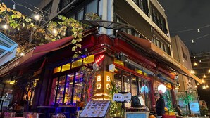 A restaurant with outdoor seating, a neon sign, and string lights. - ZULU SUITES (Istanbul)