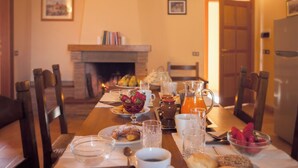 A dining table set with breakfast items, a fireplace, and a kitchen area. - Sassocupo Apartment (Arezzo)