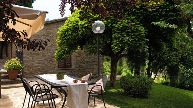An outdoor patio with a stone table, chairs, and a lamp post. - Sassocupo Apartment (Arezzo)