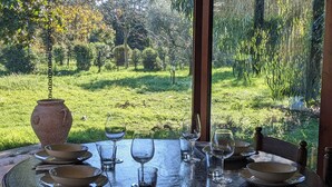 Mesa dispuesta para comer con vista a un jardín exuberante.
