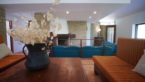 Un salón con una mesa de madera, sofás azules, una chimenea y una pared de ladrillo.