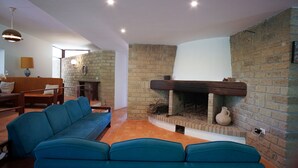 Una sala de estar con chimenea de ladrillo, sofá azul y muebles de madera.