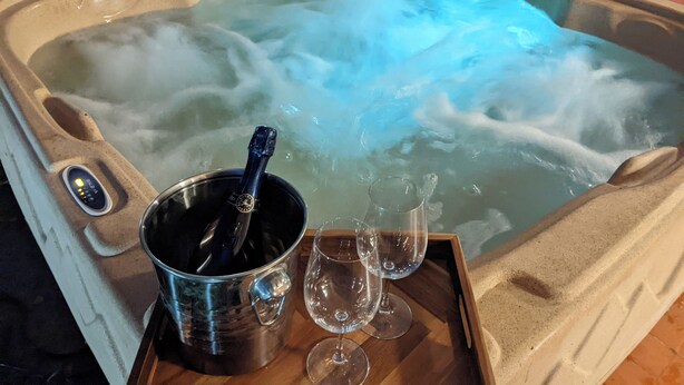 Un jacuzzi con una botella de champán y copas sobre una bandeja.