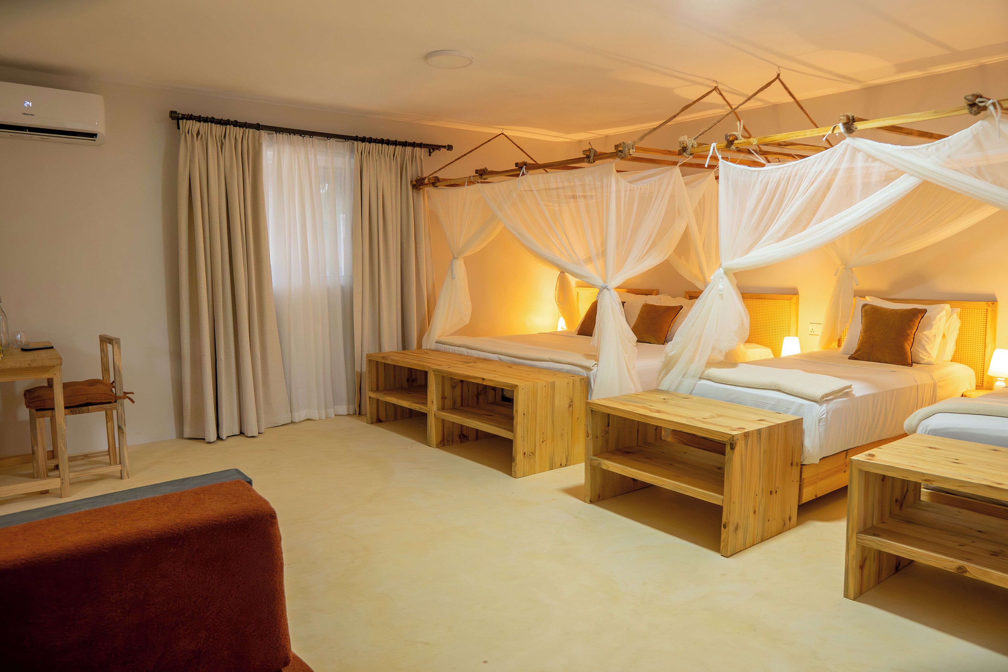 A bedroom with a canopy bed, bedside tables, a wooden bench, a chair, and a desk.