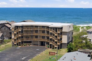 A multi-story building with a curved facade, a parking lot, and a view of the ocean.