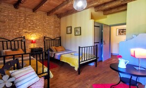 Ein gemütliches Zimmer mit zwei Betten, Holzboden und Steinwand.