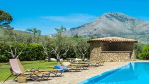 Zona de piscina con sillones de descanso y una estructura de piedra.