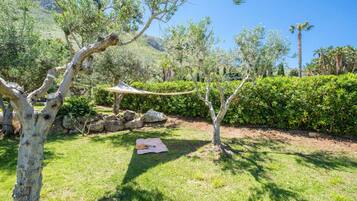A garden with a hammock, a picnic table, and a stone wall.