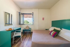 Ein Schlafzimmer mit Bett, Schreibtisch, Stuhl, einem Fenster mit Blick und einem Kleiderschrank.