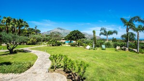 A landscaped garden with a stone pathway, palm trees, and a mountain in the background. - L Ulivo Blu - One-bed 2 With Seaview Balcony -loc (Castellammare del Golfo)