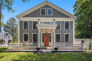 A two-story house with a front porch, a red door, and a mailbox.
