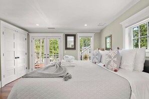 A spacious bedroom with a large bed, a view of the outdoors through a sliding door, and a white wardrobe.