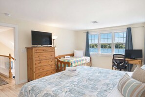 A bedroom with a bed, a dresser, a desk with a computer, and a television.