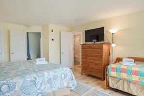 A bedroom with a bed, a dresser, a television, and a lamp.