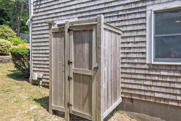 A wooden shed with a sliding door, positioned next to a house with siding and a window. - Waterfront on Follins Pond! (Dennis)