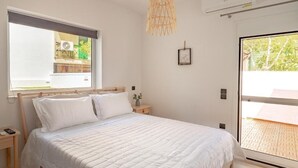 Un dormitorio con cama, mesitas de noche, lámpara colgante, ventana y equipo de aire acondicionado.