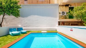 Piscina con cubierta de madera y cojines azules.