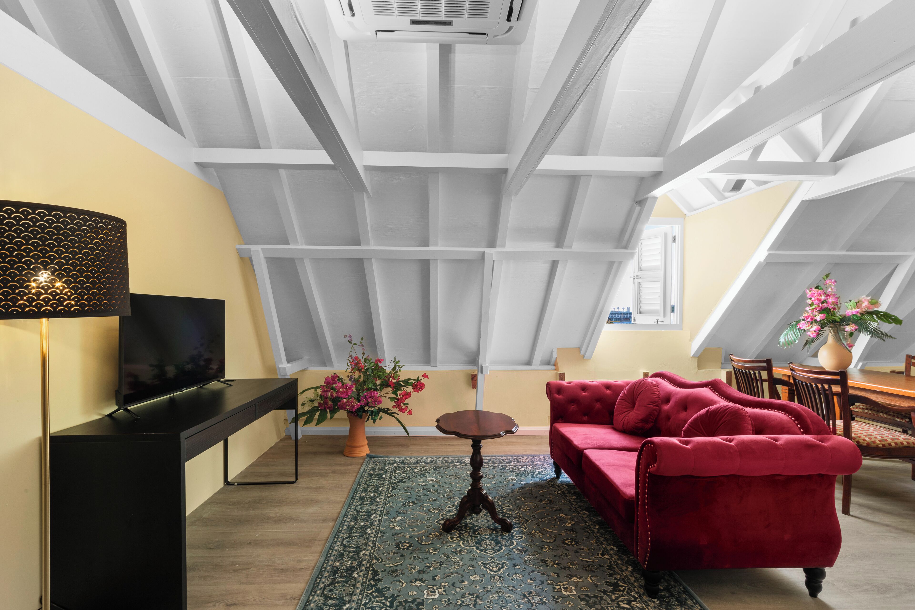 A modern loft with a high ceiling, a flat-screen TV, a red sofa, and a dining area.