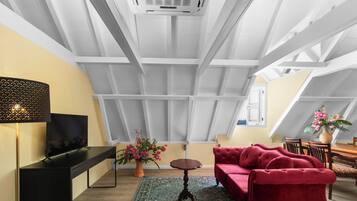 A modern loft with a high ceiling, a flat-screen TV, a red sofa, and a dining area.