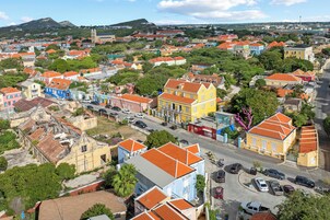 Vista aérea de un pueblo con edificios coloridos, una iglesia destacada y una carretera despejada.