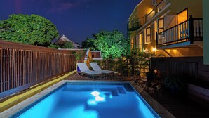 A swimming pool with lounge chairs, a wooden deck, and a building with balconies. - Drift Hotels  (Willemstad)