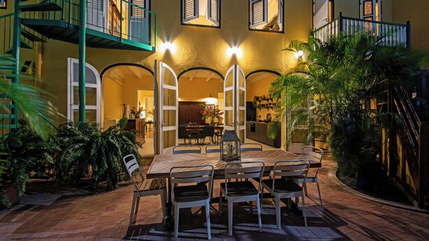 A patio with a dining table and chairs, surrounded by plants and a staircase. - Drift Hotels  (Willemstad)