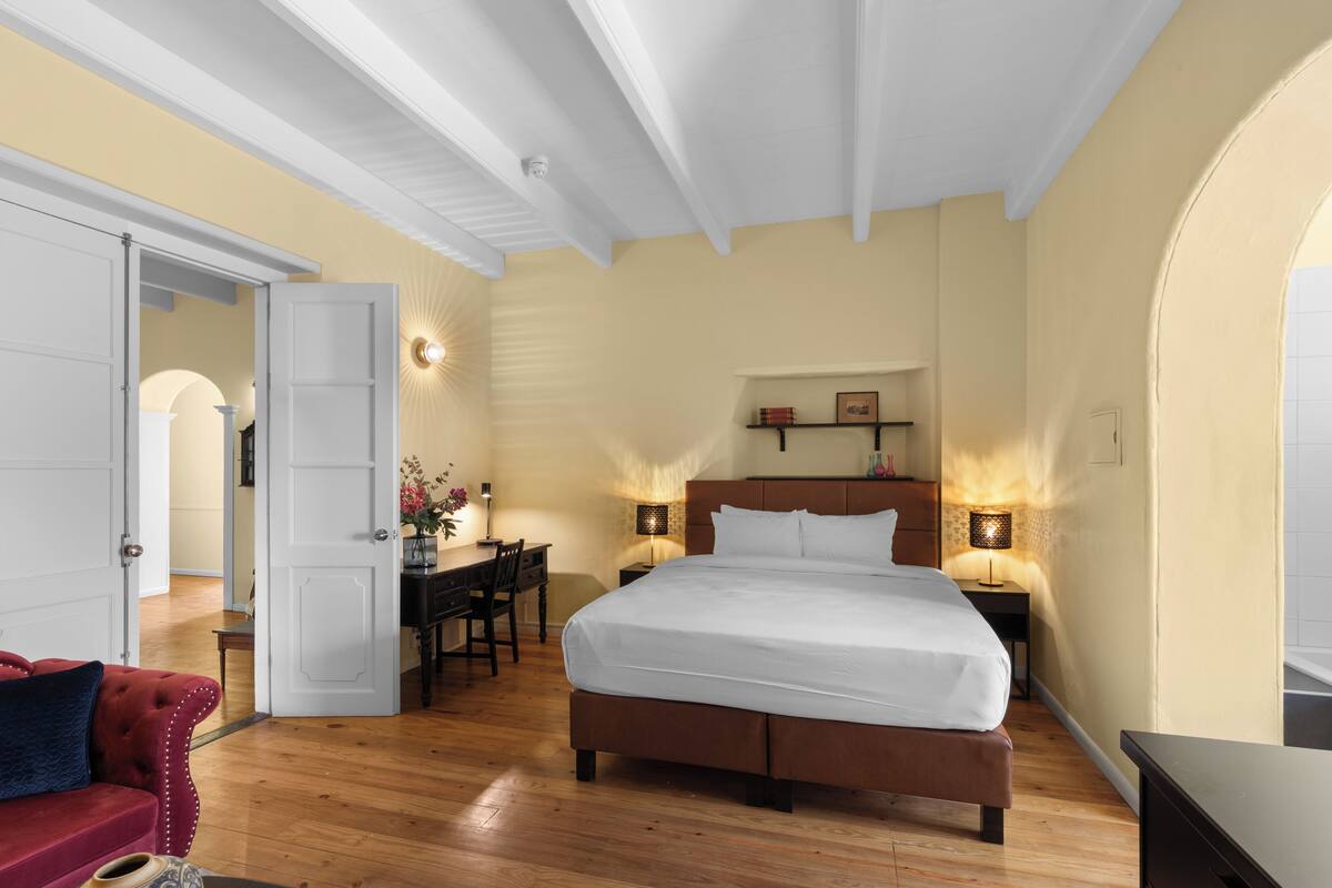 A bedroom with a large bed, a desk, and two bedside lamps.