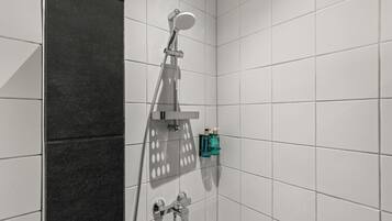 Une salle de bain moderne avec des carreaux blancs, une douche équipée d’un pommeau de douche à main et un porte-serviettes.