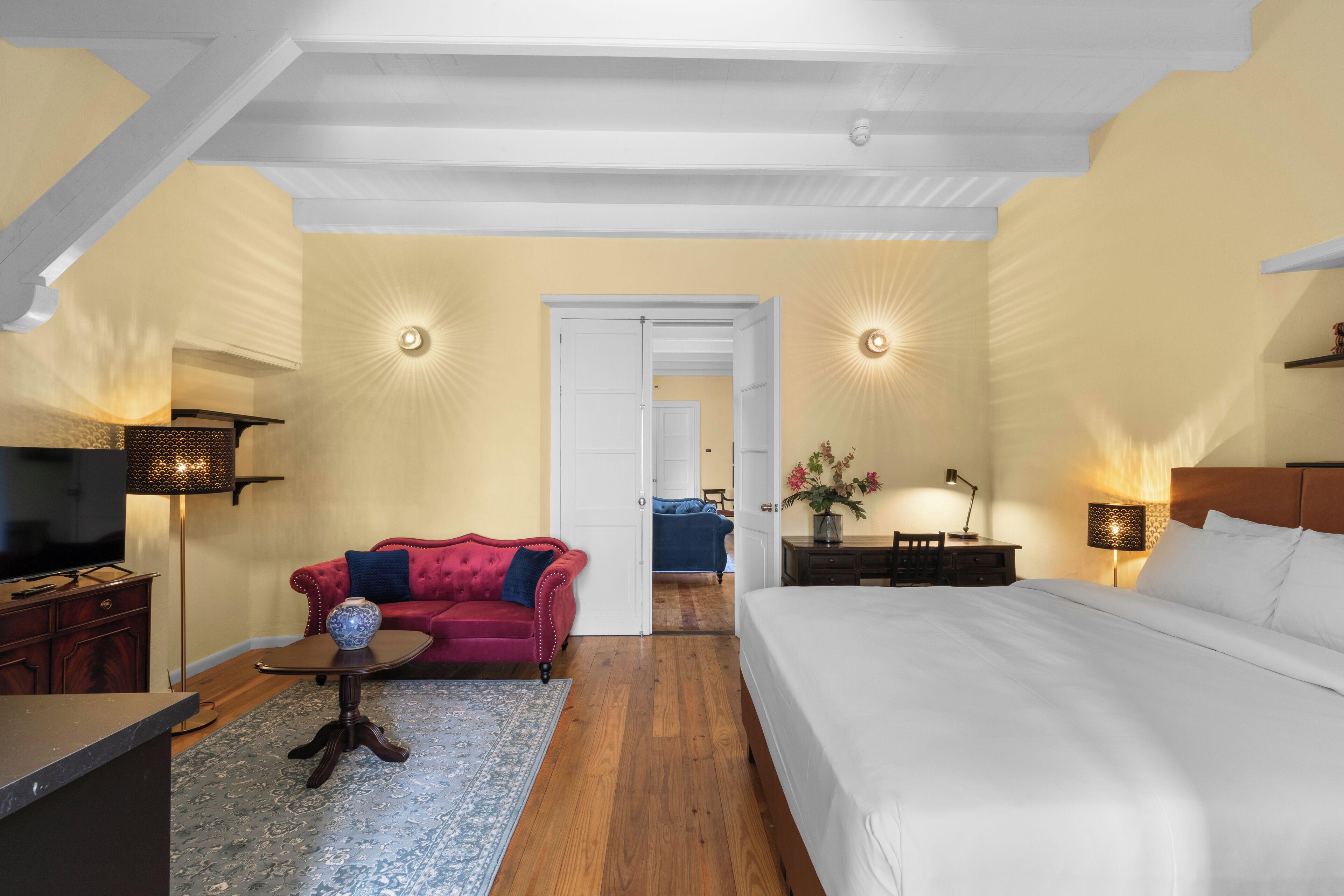 Une chambre d’hôtel avec un grand lit, un canapé rouge, une petite table et un téléviseur.