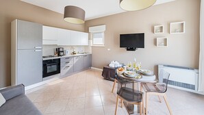 A modern kitchen with a dining area, a flat-screen TV, and a built-in air conditioning unit. - Residenza Miralago - 17 Versilia - LOC BK (Desenzano del Garda)