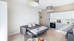 A modern, compact living space with a sofa bed, kitchenette, and breakfast setup. - Residenza Miralago - 17 Versilia - LOC BK (Desenzano del Garda)