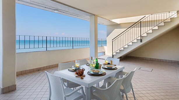 A dining area with a view of the sea, a staircase, and a tiled floor. - Residenza Miralago - 24 Clodia - Locazione BK (Desenzano del Garda)