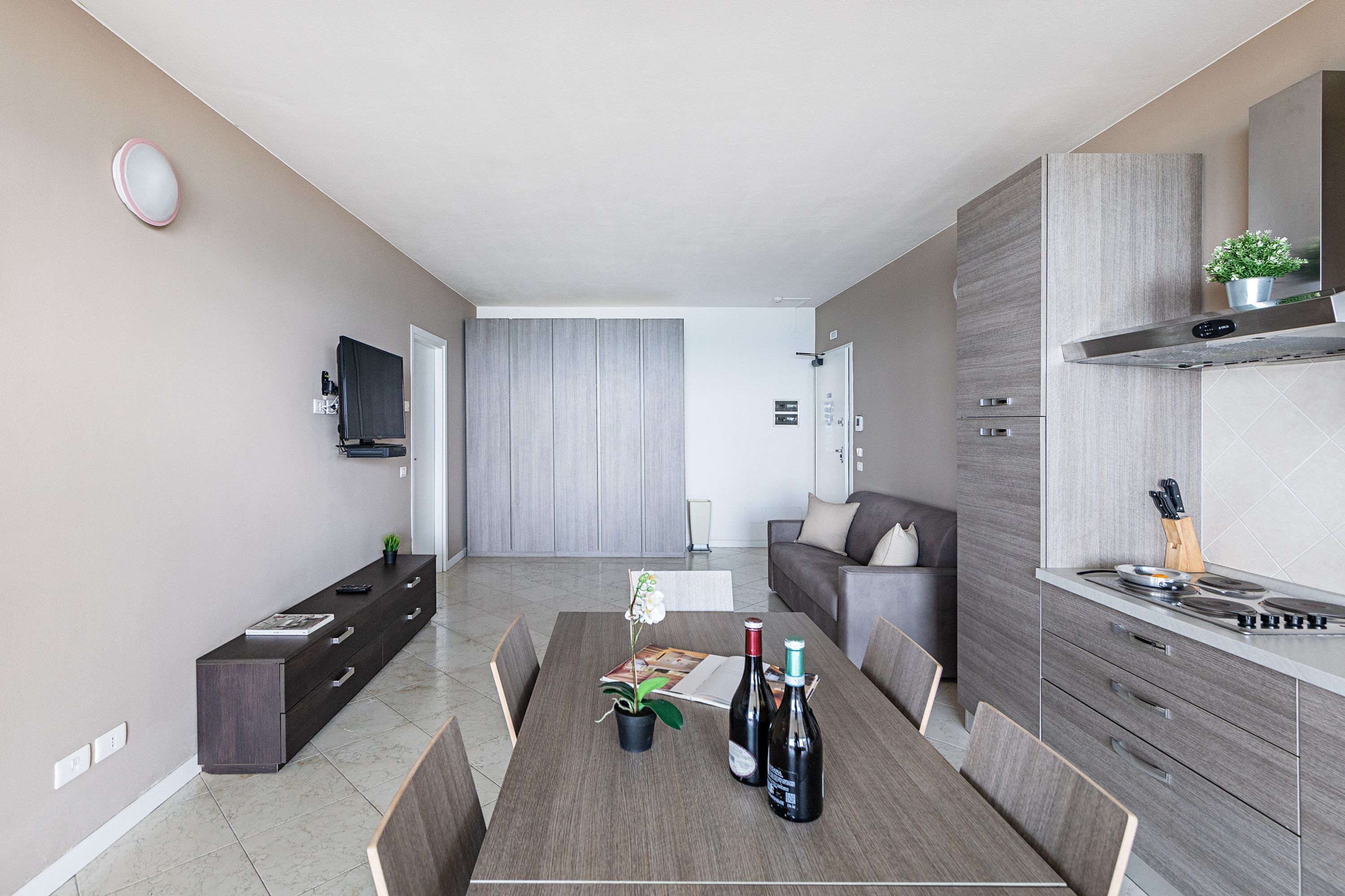 A modern living room with a dining table, sofa, and kitchen area.