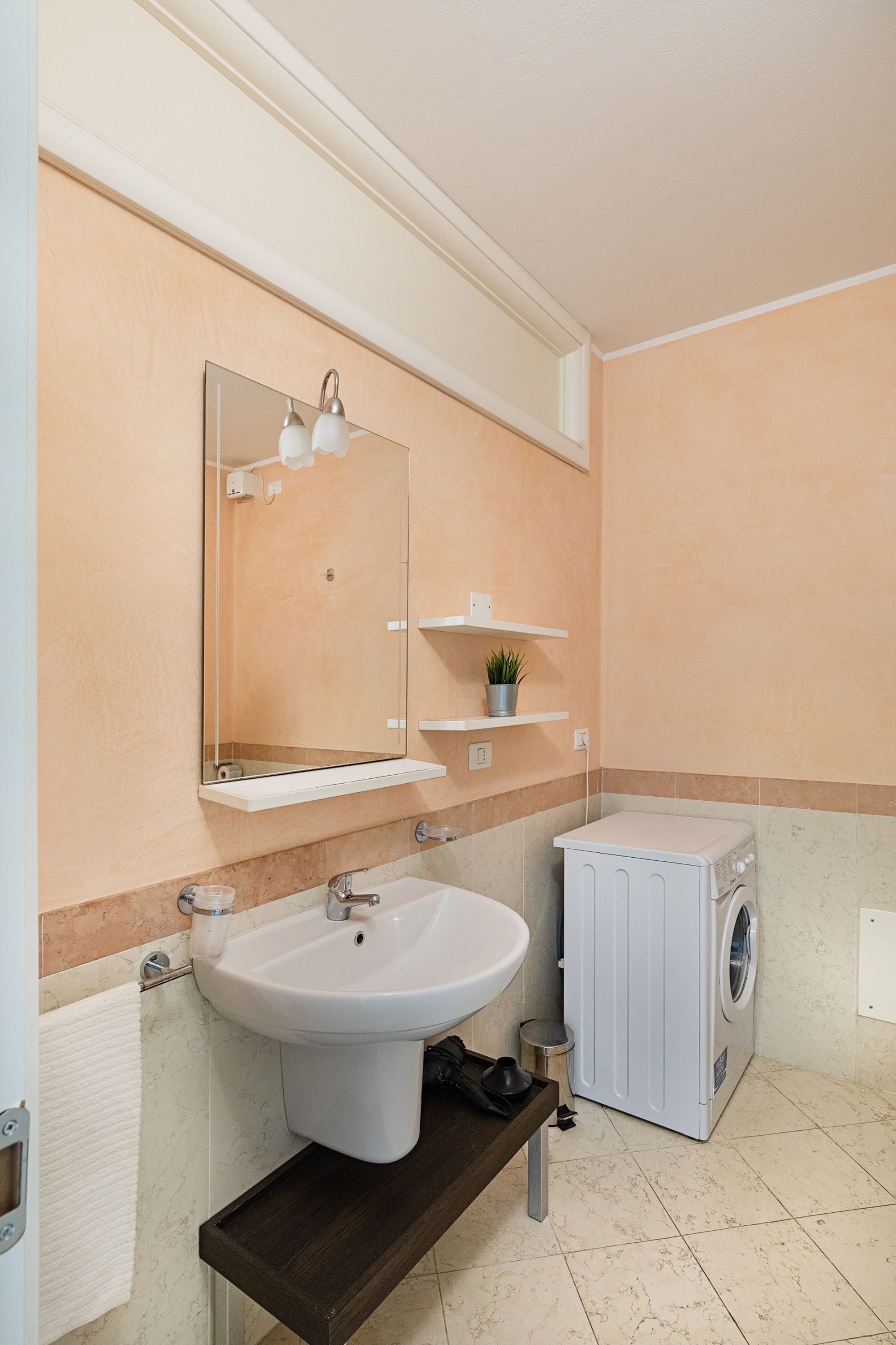 A bathroom with a sink, mirror, and a washing machine.