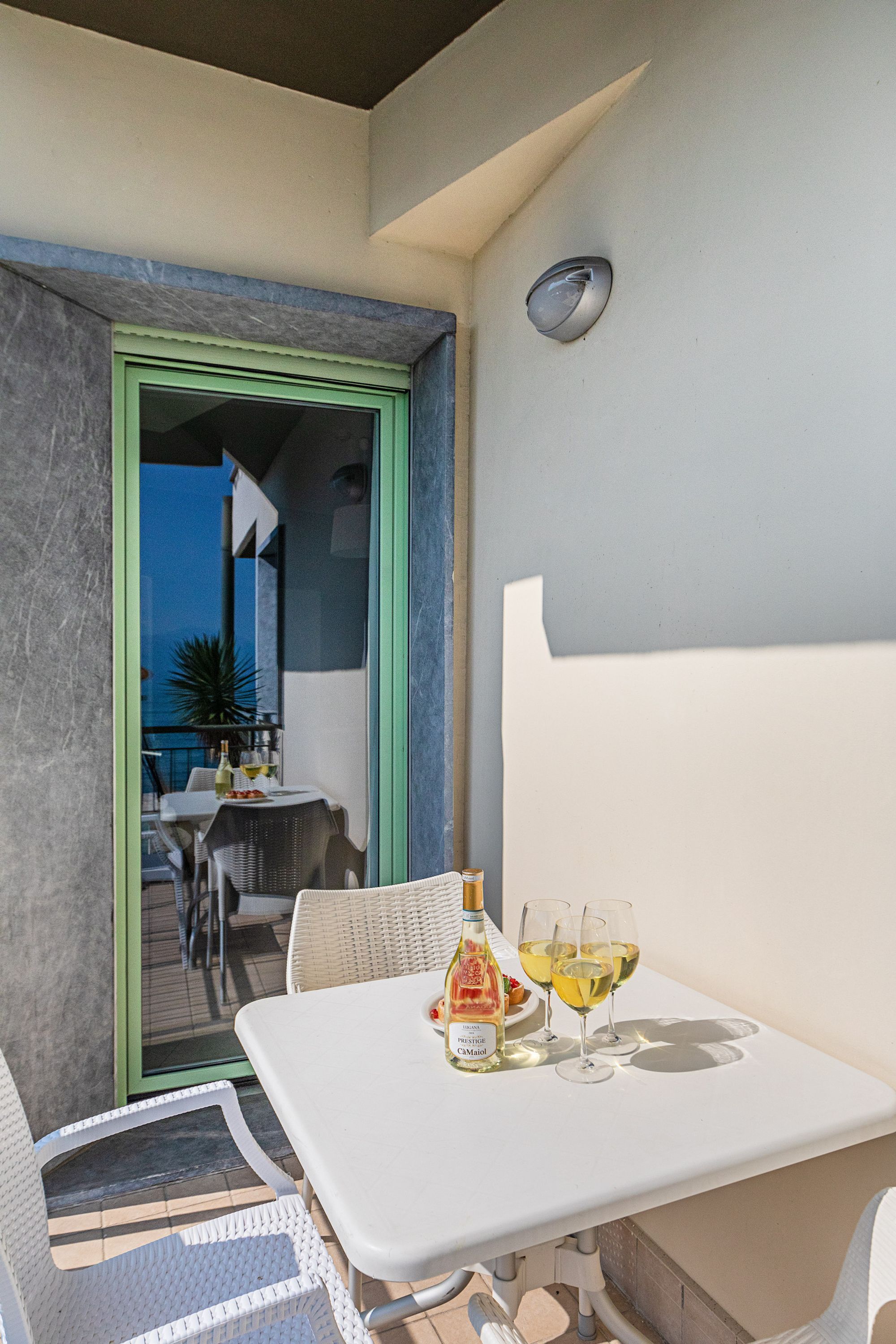 Ein Balkon mit Tisch, Stühlen und einer Weinflasche.