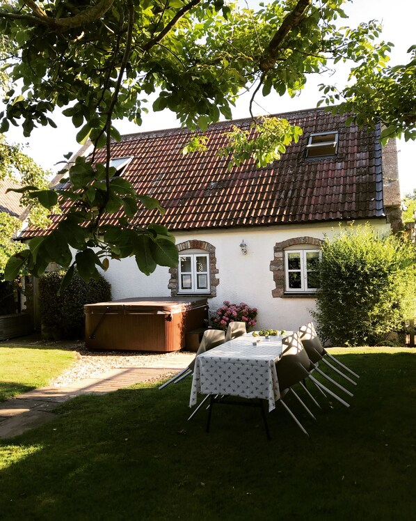 A house with a tiled roof, a patio with a table and chairs, and a garden area. - Charming 1-bedroom Annex,hot tub in stunning mendip retreat, near BristolAirport (Churchill)