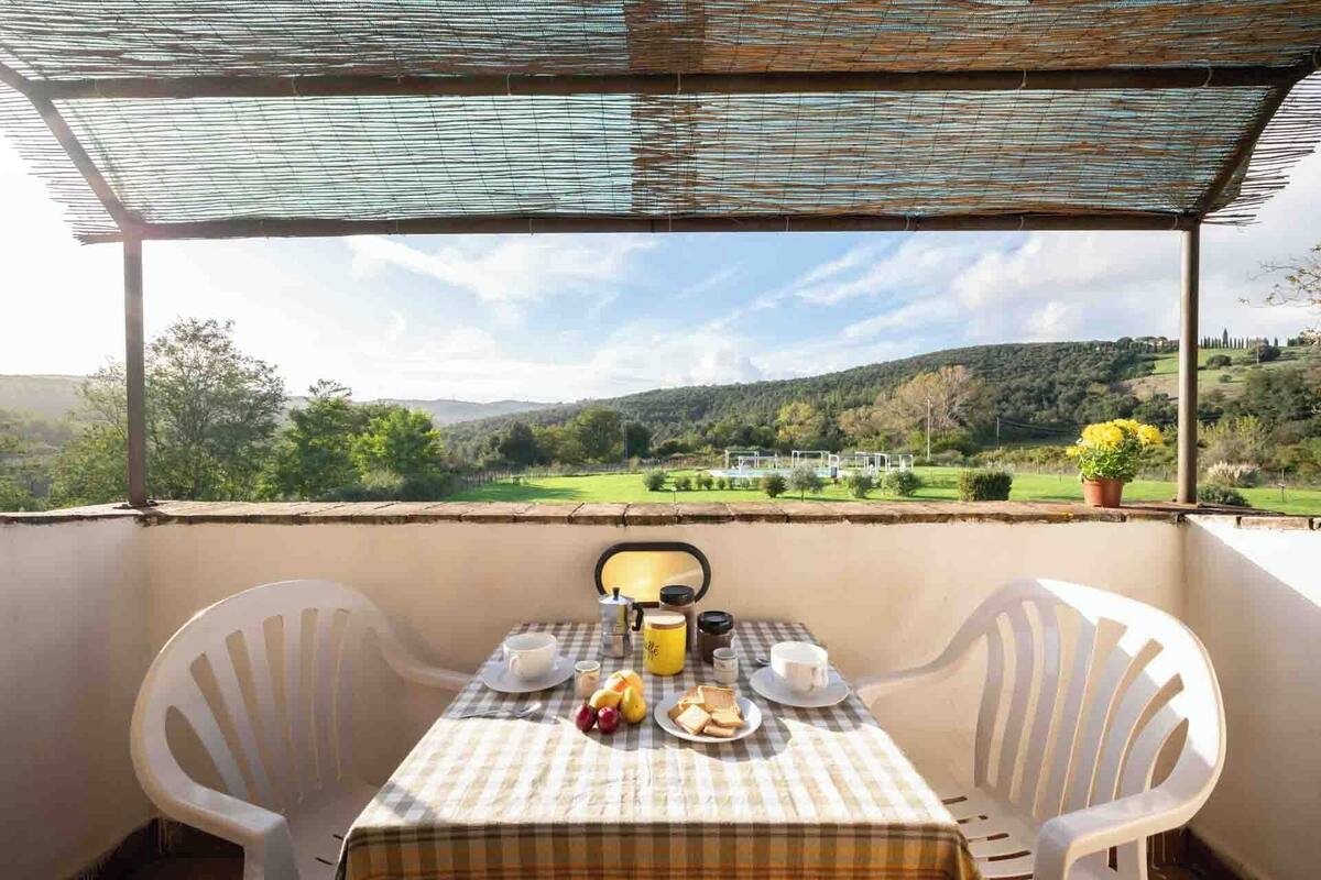 A balcony with a table set for breakfast, overlooking a scenic landscape.