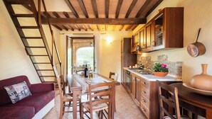 Una cocina acogedora con armarios de madera, un comedor con mesa y sillas, y un sofá rojo con un cojín estampado.