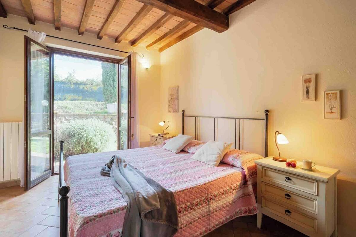 A bedroom with a bed, bedside tables, and a view through a glass door.