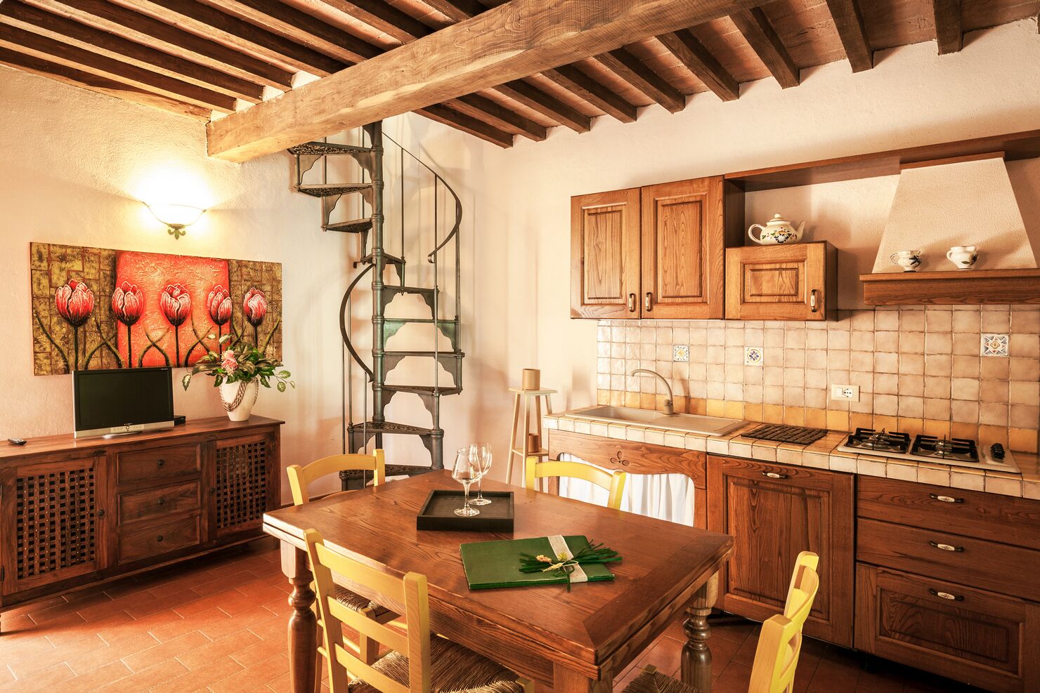 Una cocina rústica con armarios de madera, salpicadero de azulejos y una escalera de caracol.