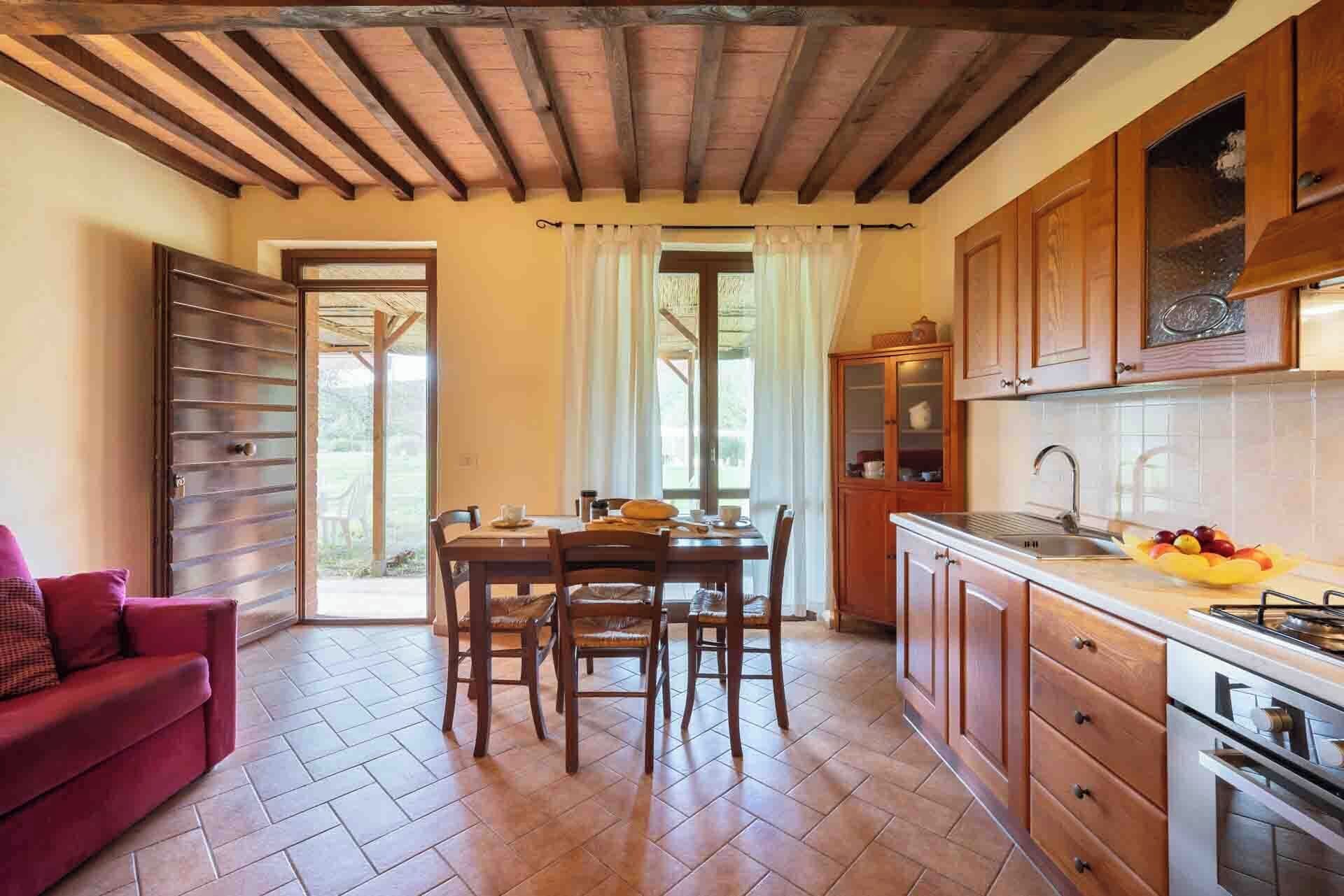 Une cuisine chaleureuse avec des meubles de rangement en bois, une table à manger avec des chaises et un canapé rouge.