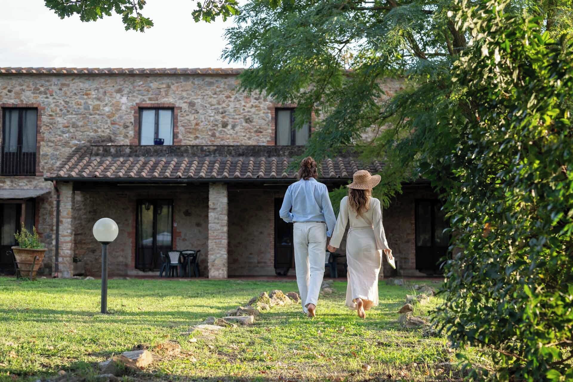 Un bâtiment en pierre avec un toit en tuiles, une cour gazonnée et un chemin dallé.
